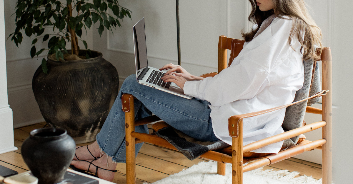 Website copywriter sitting in leather chair and typing on laptop