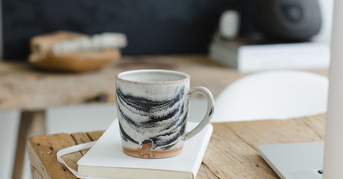 black and white mug next to laptop